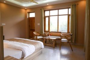 a bedroom with a bed and a desk and a window at Zankhrpas A Himalayan Home - Manali in Manāli