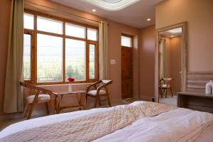 a bedroom with a bed and a table and chairs at Zankhrpas A Himalayan Home - Manali in Manāli