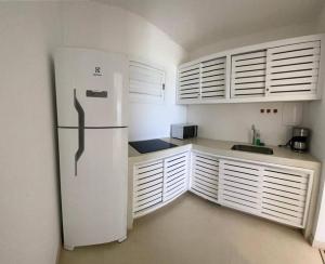 a kitchen with a white refrigerator and white cabinets at Apartamento Natureza Pipa Privilege in Pipa