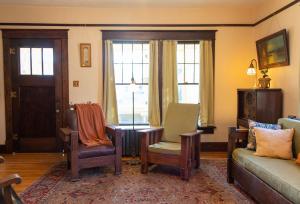 a living room with chairs and a couch and windows at The Historic Benham-Johnston Bungalow in Sheridan