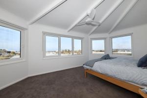 een slaapkamer met witte muren en ramen en een bed bij Bluff Vista in Ocean Grove