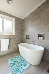 een badkamer met een wit bad en een tapijt bij Bluff Vista in Ocean Grove +9 foto's