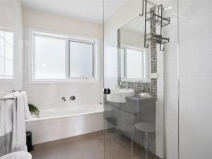 een witte badkamer met een bad en een wastafel bij Oceans 10 in Ocean Grove