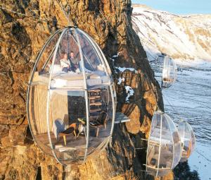 a group of people sitting in a glass dome on a mountain at OVO Patagonia in El Chalten