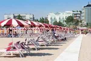 a row of chairs and umbrellas on a beach at Hotel De Londres in Rimini