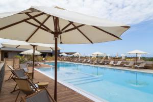 een groot zwembad met stoelen en een parasol bij Dina Morgabine Saint Gilles in Saint-Gilles-les-Bains