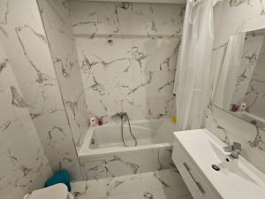 チュニスにあるJolie apprartementの浴槽と洗面台のある白いバスルーム