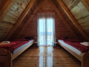 two beds in a attic room with a window at Vila Bella in Žabljak