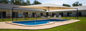 a swimming pool with a large umbrella over it at Roma Explorers Inn in Roma
