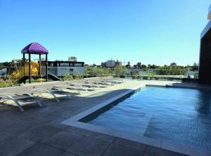 a swimming pool with lounge chairs and a gazebo at Apto a estrenar en Punta in Punta del Este