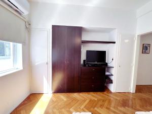 a living room with a television and a wooden cabinet at Amplio monoambiente en Microcentro in Buenos Aires