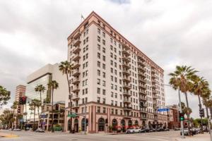 a large white building on a city street with palm trees at Chambre de Bonne in Downtown Long Beach in Long Beach