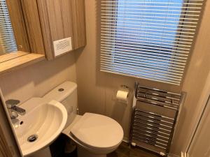 a small bathroom with a toilet and a sink at 3BR-Sleeps6-Parking-Pool-NearBeach&Skegness in Skegness +4 photos