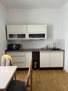 a kitchen with white cabinets and a sink and a table at Marktblick in Radeburg