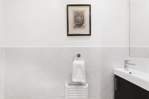 a white bathroom with a sink and a mirror at Paddington Apartment By Morethanstays in London