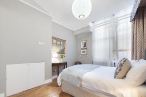 a white bedroom with a bed and a window at Paddington Apartment By Morethanstays in London