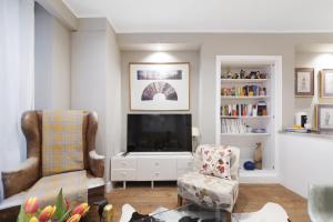 a living room with a tv and two chairs at Paddington Apartment By Morethanstays in London