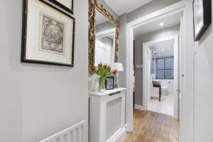 a hallway with a mirror and a vase of flowers at Paddington Apartment By Morethanstays in London