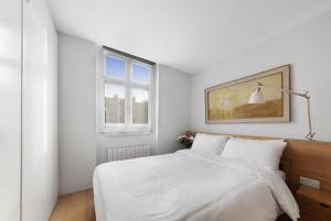 a bedroom with a bed with white sheets and a window at Crawford Street Apartment By Morethanstays in London