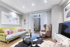 a living room with a couch and a tv at Paddington Apartment By Morethanstays in London +5 photos