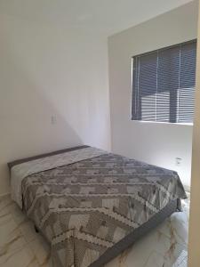 a bed in a white room with a window at Crisálias Apartamento in Foz do Iguaçu