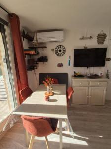 ein Wohnzimmer mit Tisch und Fernseher in der Unterkunft Havre de paix appart climatisé,piscine,wifi in Le Barcarès