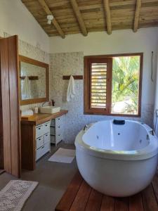 een grote badkamer met een groot bad en een wastafel bij Casa Uzêda Trancoso in Porto Seguro