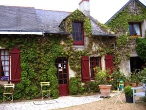 an ivycovered house with red doors and chairs at La Poiriere in Chemellier