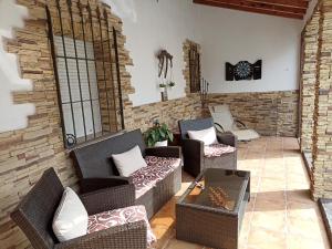 a living room with wicker chairs and a stone wall at Ala Pa cá in Miajadas