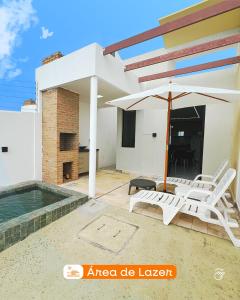 a patio with two white chairs and an umbrella at 01 - Saint Marie Beach House in Conde