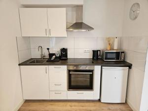 a kitchen with white cabinets and a microwave at Exklusiv Appartement - Jacuzzi Grens van Enschede! in Gronau