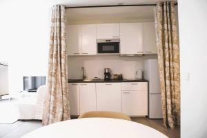 a small kitchen with white cabinets and a table at Charming Studio close to city centre in Luxembourg