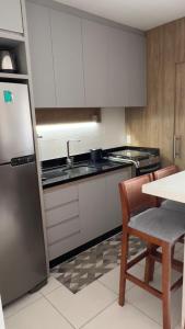 a kitchen with white cabinets and a table and a refrigerator at Apartamento novo perto da praia e Beto Carrero in Piçarras