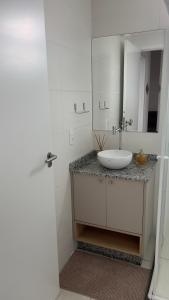 a white bathroom with a sink and a mirror at Apartamento novo perto da praia e Beto Carrero in Piçarras