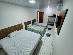 a bedroom with two beds and a tv in it at Apartamento em Lins - apto 04 in Lins