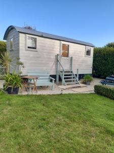 CarleenThe Shepherd Hut的一个小房子,配有野餐桌和长凳