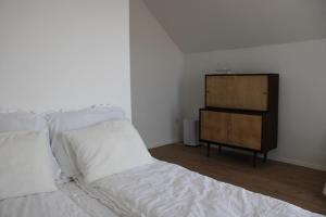 a bed with white sheets and a dresser in a room at Villa Zöldvölgy - Lassulj le és töltődj fel nálunk in Szůcsi