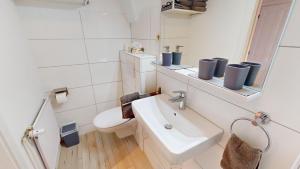 ein weißes Badezimmer mit Waschbecken und Toilette in der Unterkunft Ferienhaus Knippschild in Norderney