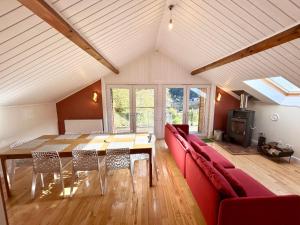 a dining room with a table and a red couch at Chalet des roches - Plainfaing in Plainfaing