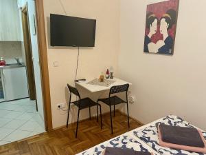 a room with a table and two chairs and a television at Kristina Apartmanház in Dobrinj