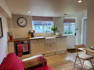 a kitchen with a couch and a clock on the wall at The Cottage at Yewtree Farmhouse in Newbury