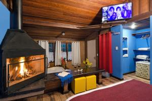 a living room with a fireplace and a tv at Pousada Olho D'Água in Visconde De Maua