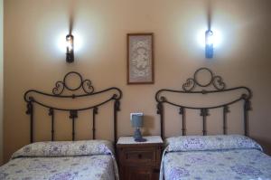 two beds in a bedroom with two lights on the wall at Casa Rural Los Olivos in Sotoserrano +44 photos