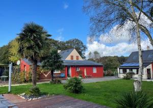 a home with a red house and a palm tree at Ty Coogee in Herbignac