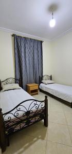 a bedroom with two beds and a window at Diar Kamiliya Meknès in Meknès