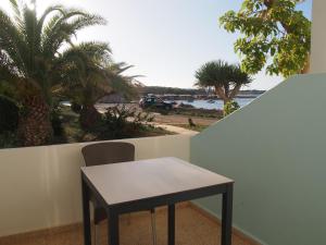 a table and a chair on a balcony with palm trees at Hotel Roca Bella in Es Pujols