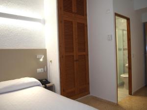 a bedroom with a bed and a bathroom with a toilet at Hotel Roca Bella in Es Pujols