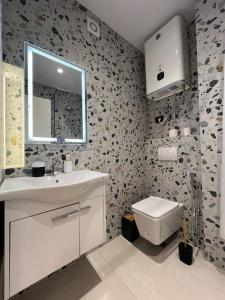 a bathroom with a toilet and a sink and a mirror at City Center Urban Condo in Tirana