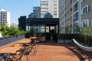 una fila de mesas y sillas de madera en un edificio en MEO! Hostel, en São Paulo