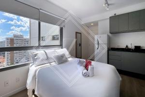 a white bed in a room with a large window at Zainalofts7Vila Mariana ao lado metrô, CASV 117 ID in Sao Paulo